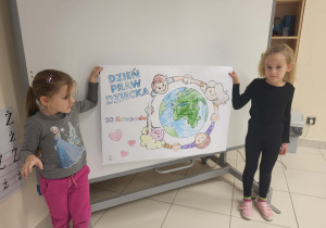 dziewczynki prezentują pomalowaną przez grupę dzieci kolorowankę