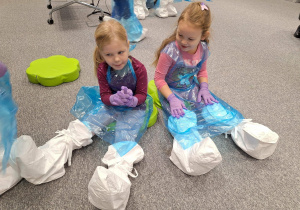 dzieci siedzą w fartuchach o ochraniaczach