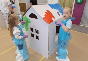 dzieci malują farbami domek