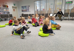 dzieci siedzą na pufkach