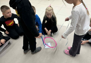 chłpiec i dziewczynka trzymają w rękach sznurki przymocowne do koła i muszą według polecenia znalezć odpowiedni obrazek z pogodą