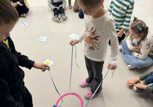 chłpiec i dziewczynka trzymają w rękach sznurki przymocowne do koła i muszą według polecenia znalezć odpowiedni obrazek z pogodą