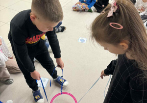 chłpiec i dziewczynka trzymają w rękach sznurki przymocowne do koła i muszą według polecenia znalezć odpowiedni obrazek z pogodą