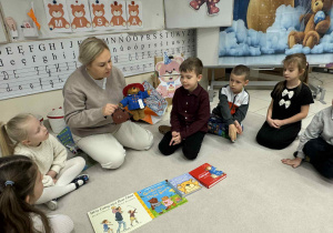 Pani pokazuje dzieciom maskotkę Misia Paddigtona