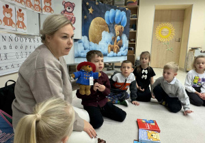 Pani opowiada dzieciom o Misiu Paddigtonie, trzymajac maskotkę