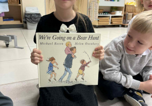 dziewczyna trzyma ksiązke anglojęzyczną "We going on the bear hunt"