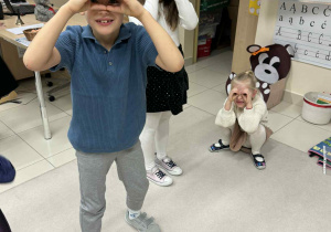 dzieci śpiewają piosenkę ruchową wykonując gest lornetki