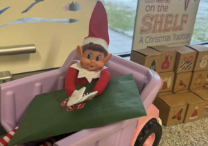 elf siedzący w samochodzie i trzymający komperte z listem