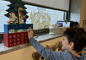 chłopiec sięga do okienka kalendarzaa adwentowego