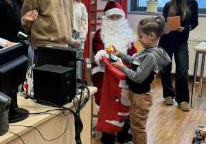 chłpiec stoi przed mikołajem i trzyma w ręku klocki