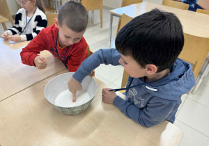 chłopcy siedzą przy stoliku i dotykają cieszy nienewtonowskiej