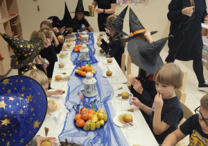 dzieci siedzą przy stole podczas poczęstunku