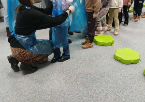 Dzieci zakładają fartuchy ochronne