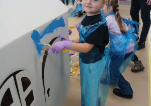 Malowanie ściany domku przez chłopca