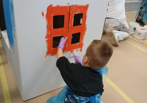 Chłopiec maluje okno