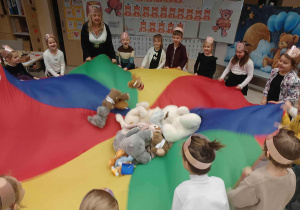 dzieci bawią się z misiami , które są na chuście