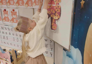 dziewczynka dopasowuje misiowi plasterek z literką