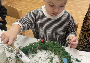 chłopiec ozdabia wianek