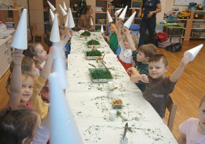 dzieci trzymają w dłoniach choinki