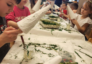 dzieci smarują choinkę klejem