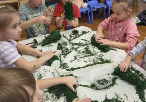 dzieci dociskają mech na choince