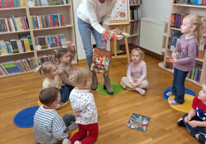 pani trzyma książkę i cukierki dla dzieci