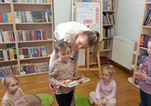 dziewczynka odbiera książkę od pani