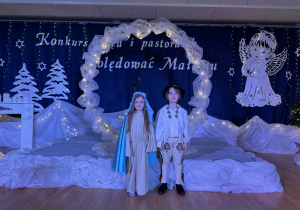 chłopiec z dziewczynką stoją na tle dekoracji