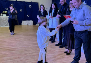 chłopiec odbiera gratulacje i nagrodę