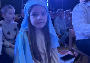 Dziewczynka przebrana za Maryję siedzi na ławce