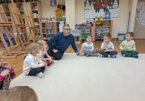 pan siedzi z dziećmi na dywanie