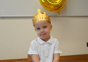 chłopiec w koronie siedzi na krześle