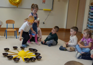 chłopiec wkłada koraliki do miseczek