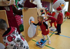 dziewczynka przyczepia bałwankowi marchewkę