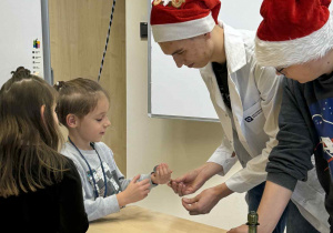 uczniowe technikum pokazują chłopcu, który trzyma magnes eksperyment