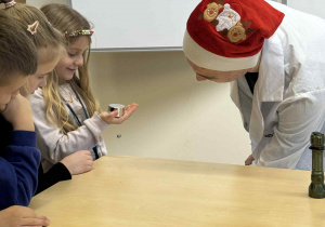 dziewczynka trzyma w ręku magnes i uczeń technikum pokazuje jej eksperyment z lewitującym magnesem