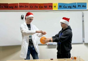 uczniowe technikum pokazują eksperyment z balonem i skórką z pomarańczy