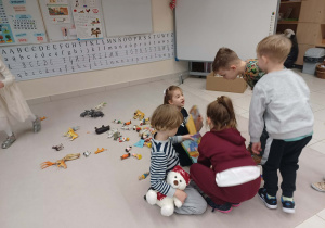 dzieci sprzątają zabawki i książki rozrzucone po dywanie