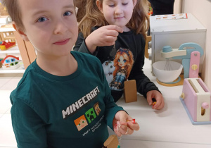 chłopiec i dziewczynka pozują do zdjęcia i pokazują co za wykonane zadanie otrzymały od elfa