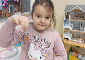 dziewczynka trzyma w dłoni pudełeczko adwentowe a w drugiej świąteczny breloczek