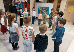 dzieci stoją w kole z panią i stoją nieruchomo, wykonując zadanie od elfa