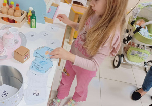 dziewczynka szuka numeru z zadaniem od elfa