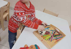 chłopiec ze zdziwioną miną pokazuję jak elf pomieszał kredki z flamastrami