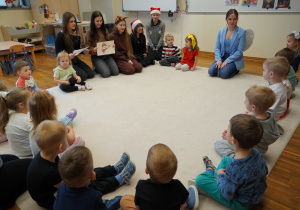 dzieci i licealistki siedzą na dywanie