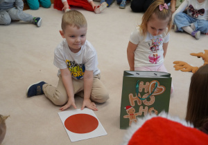 chłopiec trzyma kartkę z czerwoną kropką