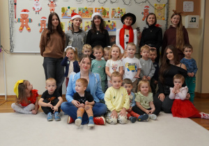 trzylatki i licealistki z nauczycielem pozują do zdjęcia