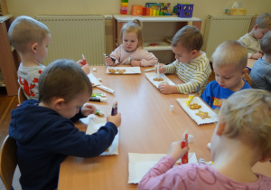 dzieci dekorują ciasteczka kolorowymi pisakami