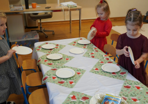 dziewczynki ustawiają talerzyki na stole