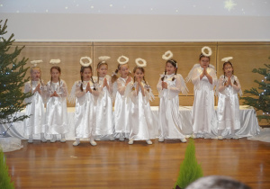 dziewczynki przebrane za aniołki śpiewają kolędę