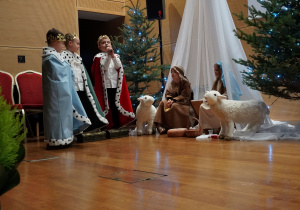 chłopcy jako trzej królowie stoją przy stajence i składają dary